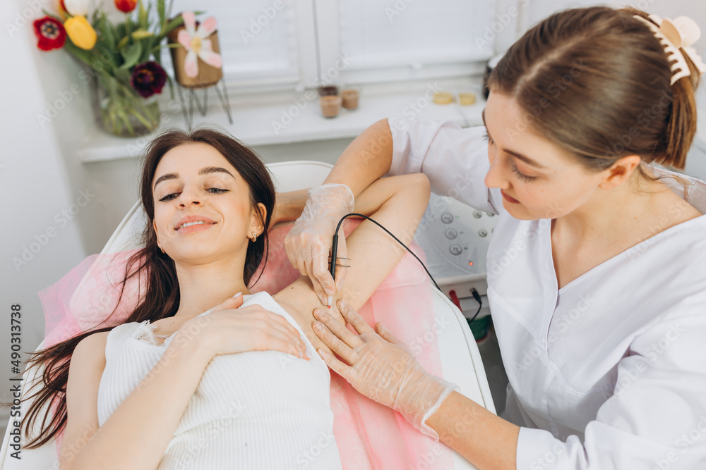 Procedure removal of hair permanently in a woman's armpits using metod electro epilation. Permanent removal of unwanted hair. The needle of electrolysis. Doctor in cosmetic medical cabinet. Procedure removal of hair permanently in a woman's armpits using metod electro epilation. Permanent removal of unwanted hair. The needle of electrolysis. Doctor in cosmetic medical cabinet.