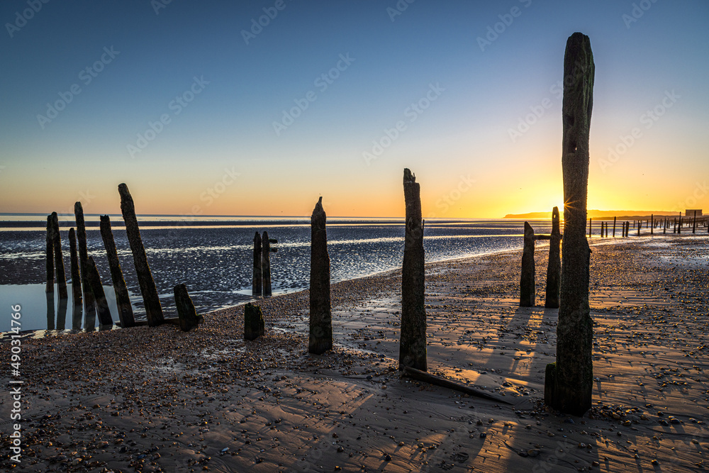 Sunset over the groynes on the beach at Rye Harbour, East Sussex, England