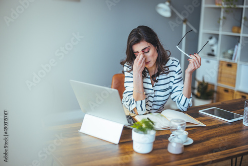 Shot of a young woman suffering from stress while using a computer at her work desk. Shot of a mature businesswoman looking stressed out while working on a laptop in an office