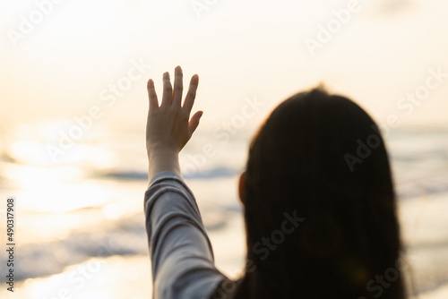 Close up hand woman touching the sunset at the evening. Traveler female walking at the beach in vacation time. Relax on holiday weekend summertime. Travel and Freedom concept.
