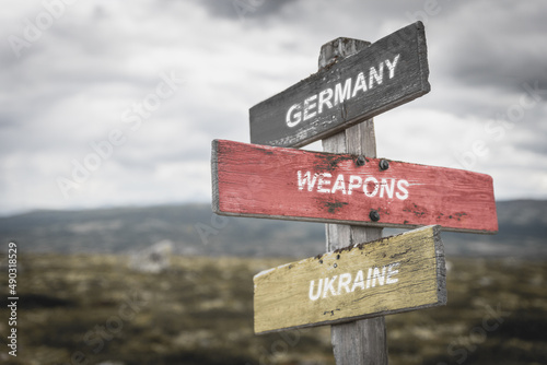 germany weapons ukraine text quote on german flag painted on wooden signpost outdoors in nature. To simulate the conflict in ukraine, europe.