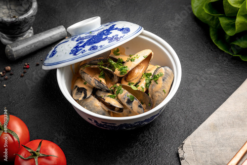 mussels in sauce in a ceramic dish on a dark decorated background