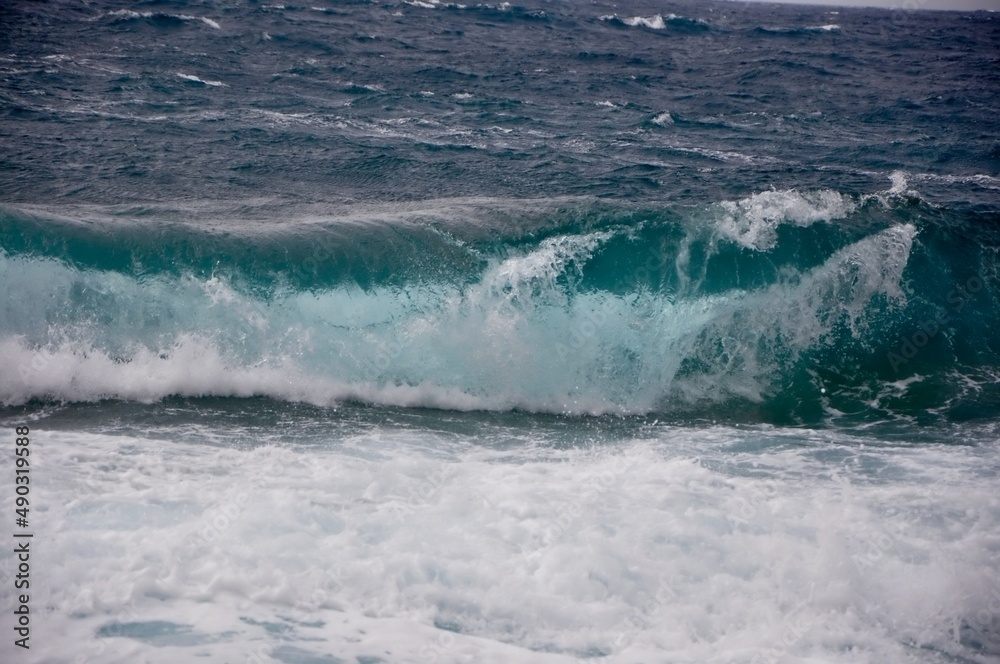 A big wave overlaps the coast of the Croatian island of Losinj. Rolling wave crashing on rocky coast.