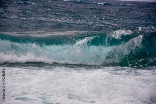 A big wave overlaps the coast of the Croatian island of Losinj. Rolling wave crashing on rocky coast.