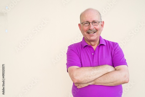 Portrait of happy senior man looking at camera smiling with arms crossed
