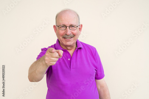 Portrait of senior man looking at camera smiling and pointing finger