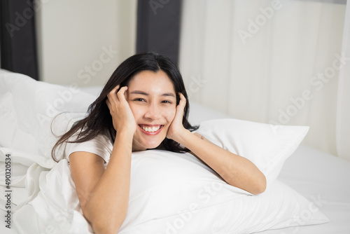 Young woman wake up before lying asleep enjoying healthy in the morning.  Beautiful asian woman sleeping well in comfortable cozy fresh bed on soft pillow white linen.