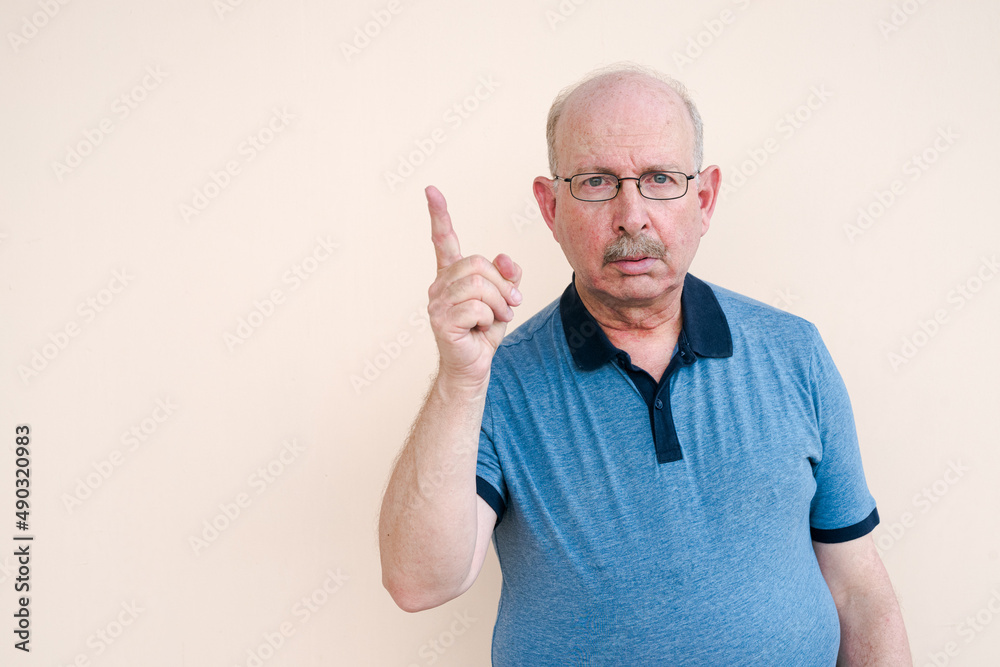Portrait of senior man looking at camera and pointing finger up Portrait of senior man looking at camera and pointing finger up