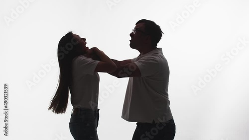 Silhouette of man from rage and anger strangling woman, white background in studio, side view. Man in fit of rage begins to strangle woman. Concept rage and madness photo