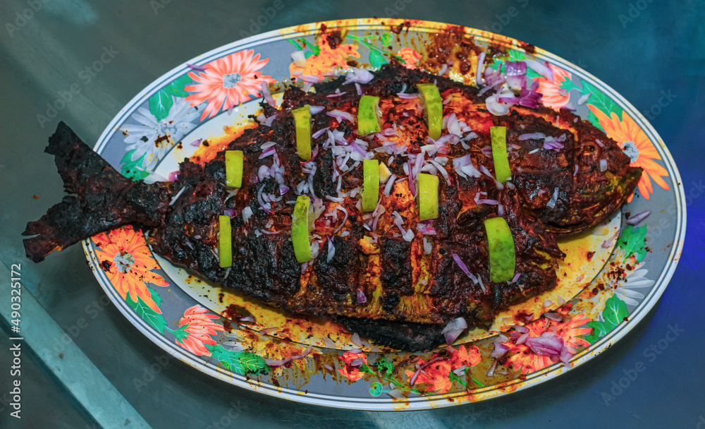 Grilled fish, sea bream with the addition of spices, herbs and lemon on the grill plate.