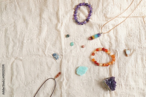 Backdrop or Flat lay background of many type of raw stone and crystal, I.e. Amethyst, Amazonite, kayanite, 7chakra pendant, placed on linen cloth with copy space in the morning light.