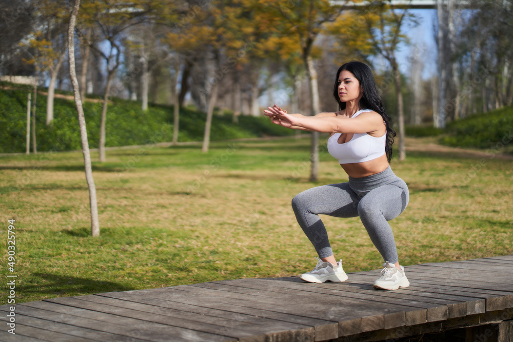 a female athlete doing squats training her legs in the park a female athlete doing squats training her legs in the park