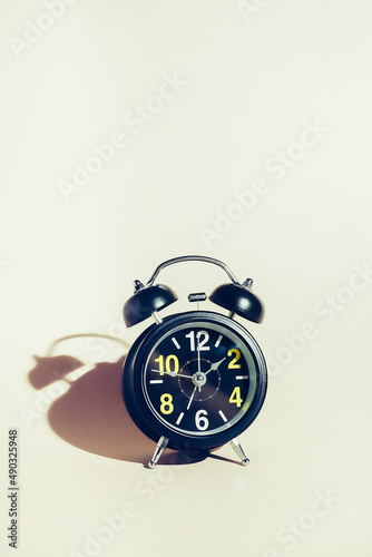 Black alarm clock with dial on beige background. Concept of time and timing with space for copying. Background.