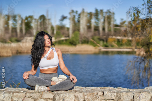 young female athlete sitting on a wall near a lake