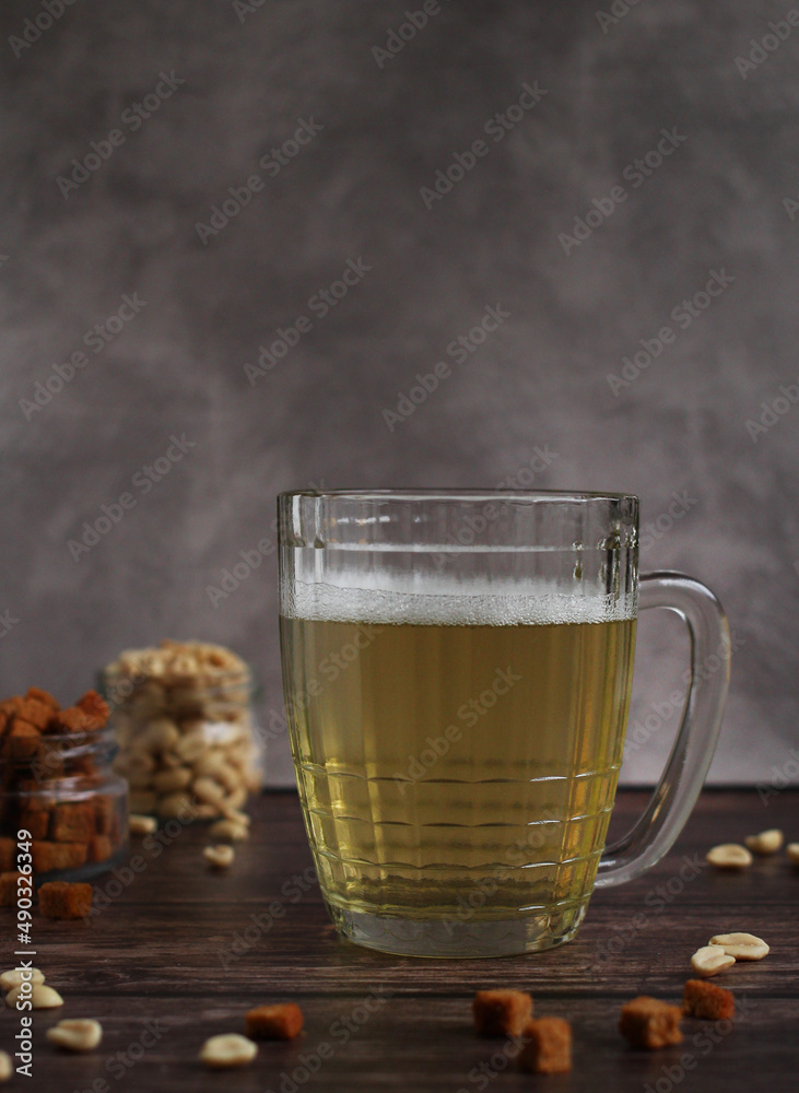 light beer in a glass mug with crackers and peanuts on a dark background light beer in a glass mug with crackers and peanuts on a dark background