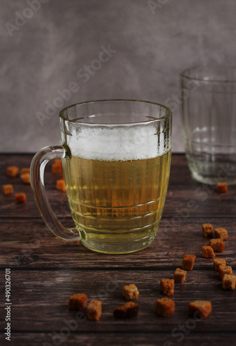 light beer in a glass mug with crackers on a dark background