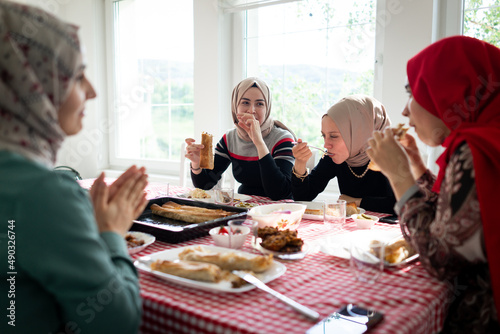 Muslim family and friends gathering together at home for eating dinner. High quality photo