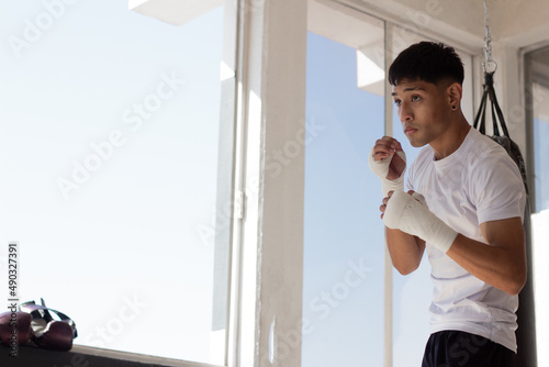 young latin boxer training by throwing punches in the air inside a gym with discipline and determination, his face is concentrated. photo