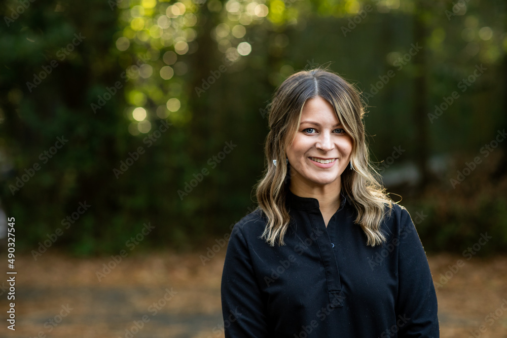 A young cosmetologist standing outside among green trees for a headshot with copy space A young cosmetologist standing outside among green trees for a headshot with copy space