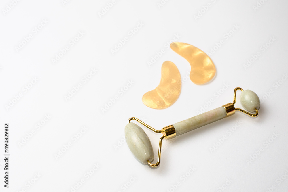 Roller face massager and patches on white background Roller face massager and patches on white background
