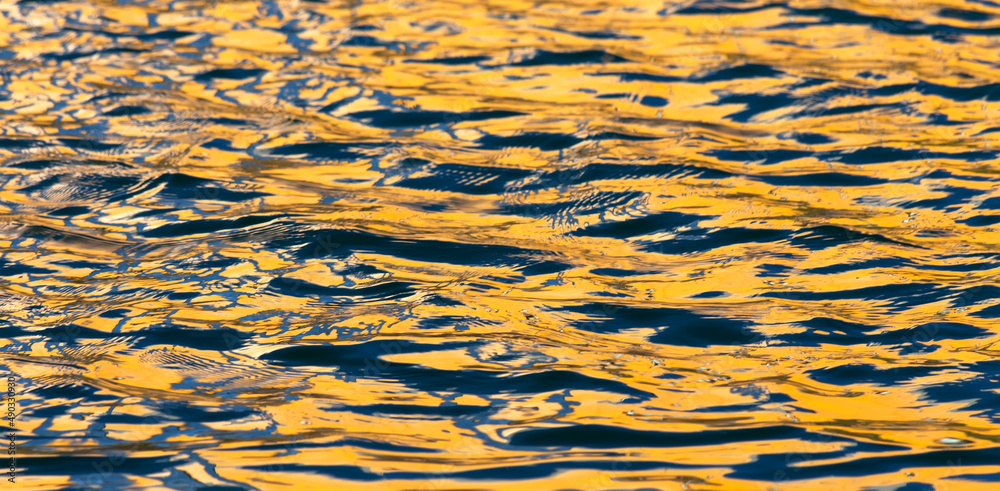 Sea waves with sunny glares, yellow and blue reflection. Abstract water background. Sea waves with sunny glares, yellow and blue reflection. Abstract water background.