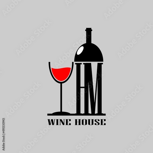 HM letter on wine bottle next to a glass of wine