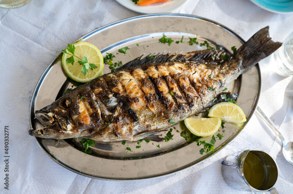 Grilled grouper fish on a silver plate in a restaurant in Crete, Greece. Grilled grouper fish on a silver plate in a restaurant in Crete, Greece.