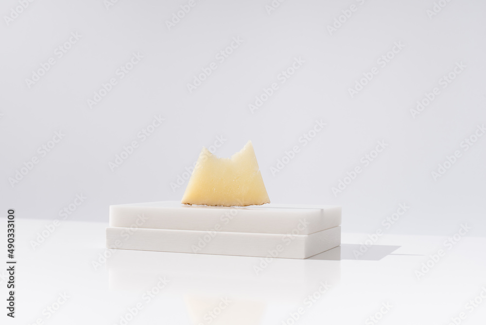 Trozo de queso manchego de oveja curado mordido sobre una mesa blanca. Aperitivo español	 - obrazy, fototapety, plakaty 