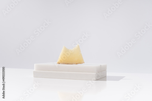 Trozo de queso manchego de oveja curado mordido sobre una mesa blanca. Aperitivo español	