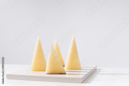 Trozos de queso manchego de oveja curado sobre una mesa blanca. Aperitivo español	 photo