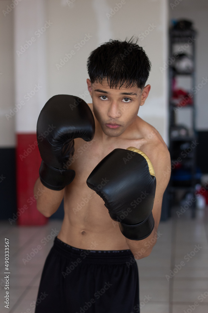 young mexican boxer posing in guard position and looking at the camera in fighting position.
