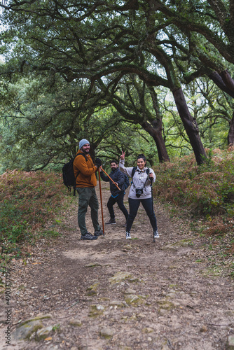 Grupo de amigos realizando senderismo por ruta de montaña rodeados de bosque