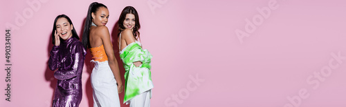 Φωτογραφία happy multiethnic women in trendy outfits posing on pink, banner