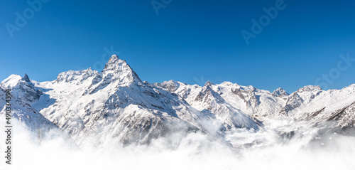Panoramic view of winter snowy mountains in Caucasus region in Russia with blue sky photo
