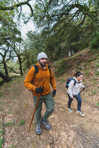 Chico alto con barba y chica joven guapa realizando senderismo por ruta verde en andalucia