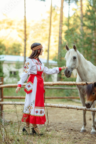 a girl in a pine forest on the background of horses