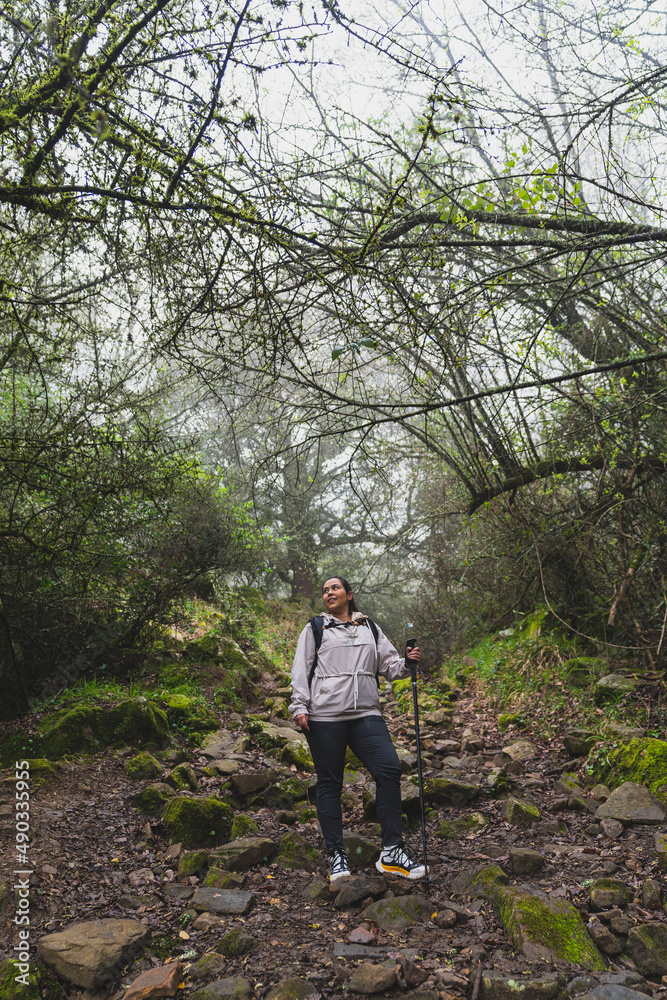 Chica joven guapa en mitad de sendero de un bosque con niebla realizando senderismo Chica joven guapa en mitad de sendero de un bosque con niebla realizando senderismo