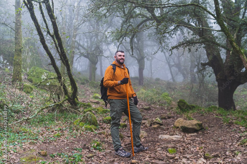 Chico alto con barba con ropa deportiva realizando senderismo por ruta verde en la sauceda con un palo de caminar Chico alto con barba con ropa deportiva realizando senderismo por ruta verde en la sauceda con un palo de caminar