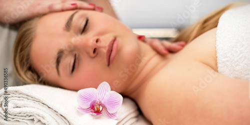 Young woman lying on massage table receiving face massage. Beauty treatment concept.