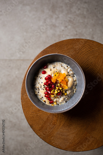 Healthy breakfast oatmeal porridge with sweet tahini, pistachio, dried apricots, pomegranate in bowl. Warm porridge oats, vegan vegetarian weight loss dieting breakfast food