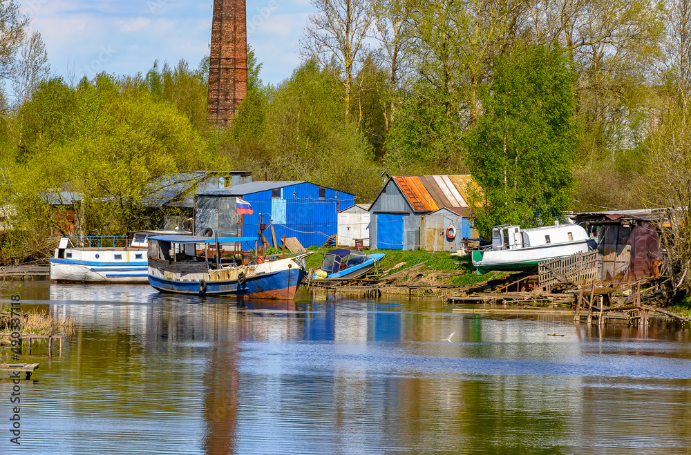 Sunny may day on the banks of the Izhora river. Abandoned boats and boats.