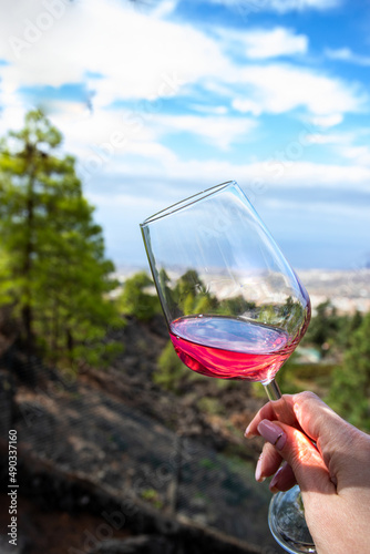 Hand holding glass with rose wine against the Beautiful mountain landscape. Exotic Hight altitude wine tasting experience.