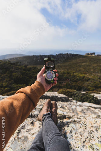 Vista en primera persona de paisaje de montaña con una mano sujetando una brújula y los pies de una persona tumbada photo