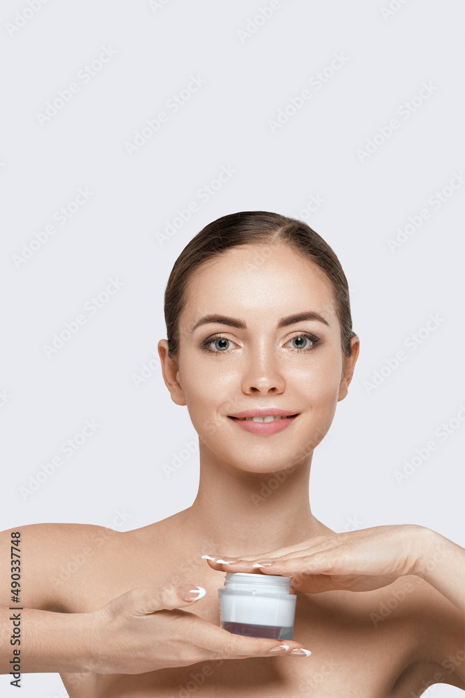 Beautiful young woman with clean fresh skin. Girl holding cream in her hand .Spa and face care Beautiful young woman with clean fresh skin. Girl holding cream in her hand .Spa and face care