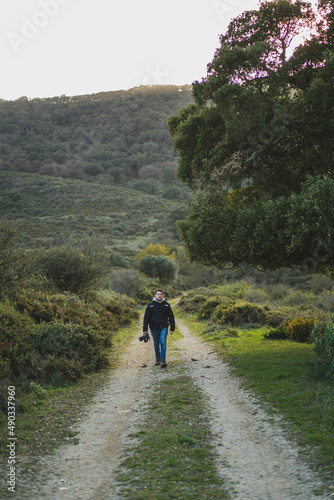 Chico joven con cámara de fotos andando por sendero de montaña realizando senderismo © MiguelAngelJunquera