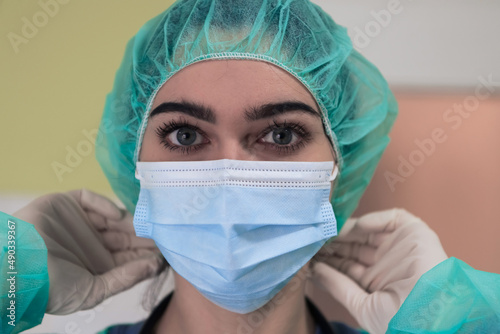 The female animal surgeon or veterinarian puts on a medical face mask. Doctor is preparing for surgery in the operation room. Medicine and healthcare