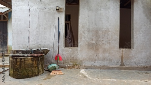 side of a poor people house with a well © ITrWorks