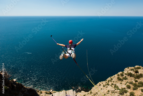 Rope jumping off a cliff with a rope in the water. The ocean. Sea. Mountain