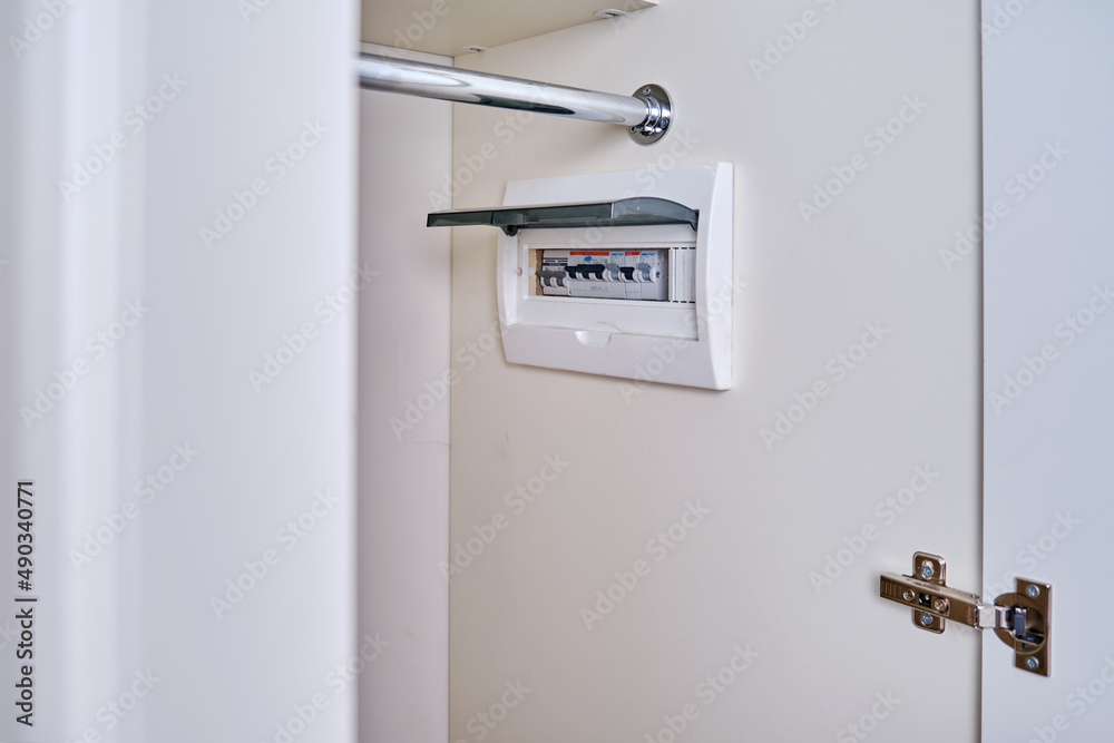 Automatic fusein a home electrical panel in the closet with clothes. Electricity equipment in the apartment, living room in the wardrobe Automatic fusein a home electrical panel in the closet with clothes. Electricity equipment in the apartment, living room in the wardrobe
