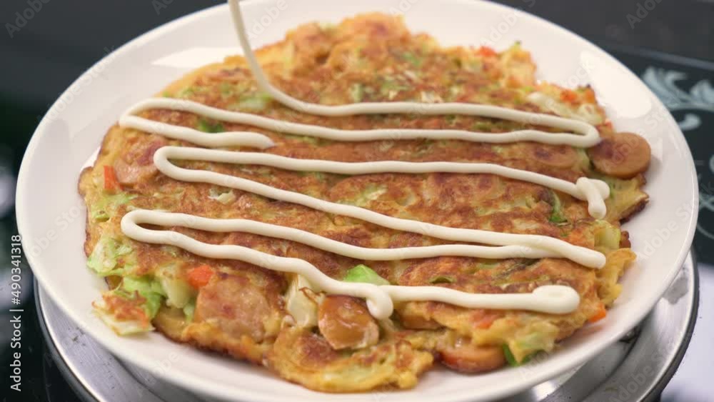 putting sauce on Okonomiyaki or Japanese pizza putting sauce on Okonomiyaki or Japanese pizza